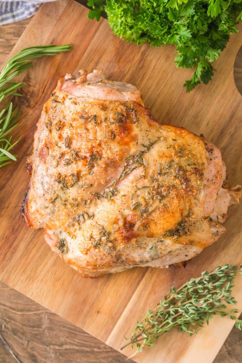 Overhead view of a Golden Brown Roasted Turkey breast that was baked with an herb butter sitting on a cutting board. Hostess At Heart