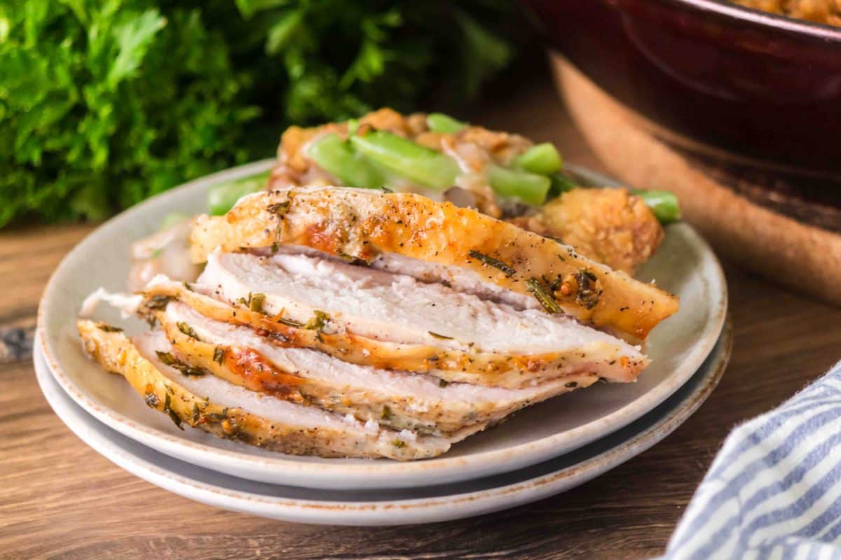 Golden brown sliced roasted turkey breast plated with a serving of green bean casserole. Hostess At Heart
