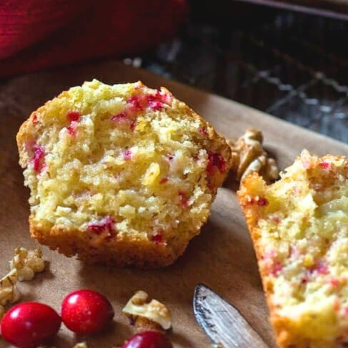 Close up view of a fluffy baked walnut cranberry muffin split in half. Hostess At Heart
