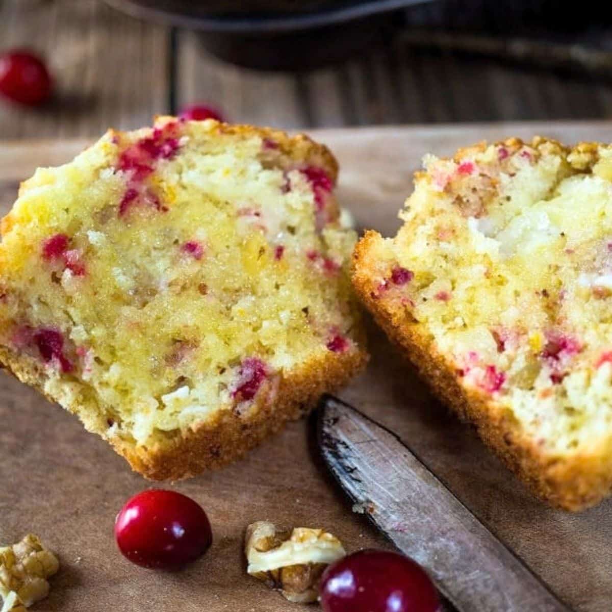 Top down view of a cranberry walnut muffin split in half showing colorful chopped cranberries and chopped walnuts. Hostess At Heart
