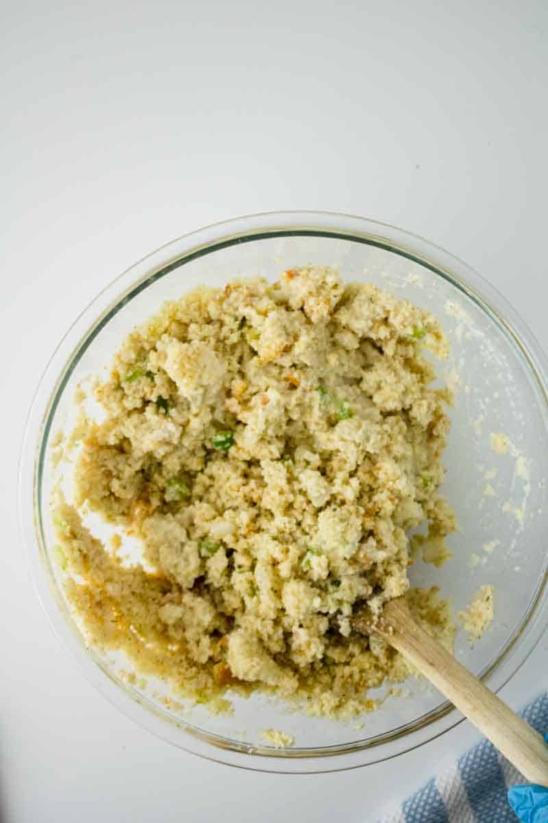 A mixing bowl filled with cornbread dressing ingredients that have been combined showing a moist fluffy cornbread dressing that's moist. Hostess At Heart