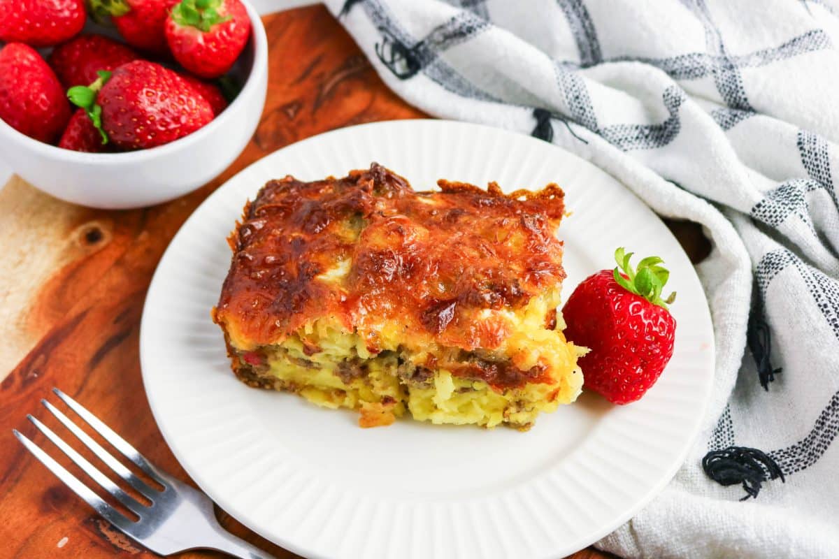 Slice of Tater Tot Breakfast Casserole with sausage, eggs, potatoes, and golden brown crispy melted cheese top. Hostess At Heart
