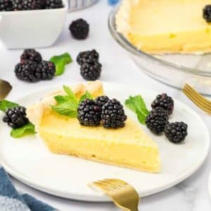 Buttermilk pie recipe slice showing a buttery crust filled with creamy vanilla custard filling and fresh blackberries. Hostess At Heart