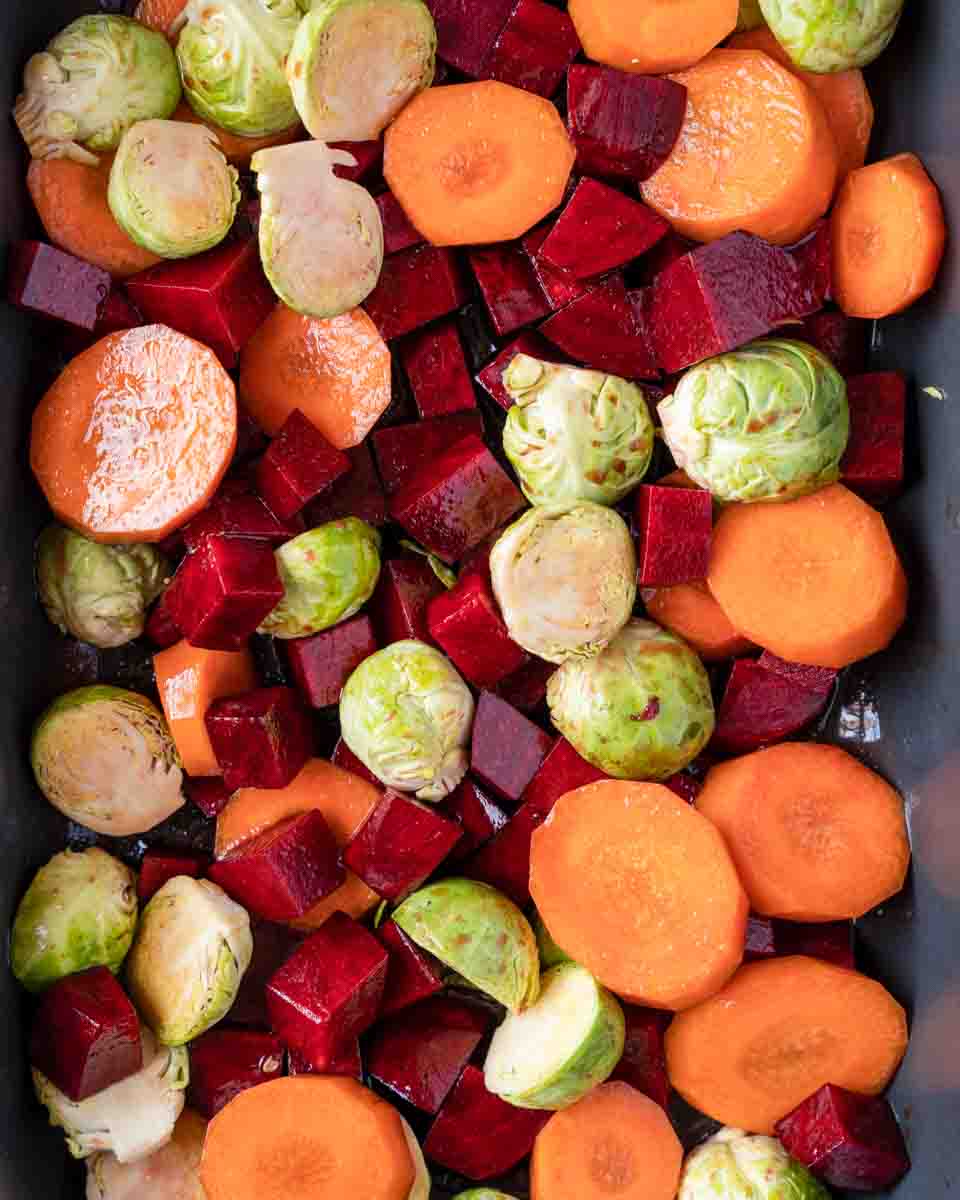 Halved Brussels sprouts added to the pan of partially roasted carrots and beets. Hostess At Heart