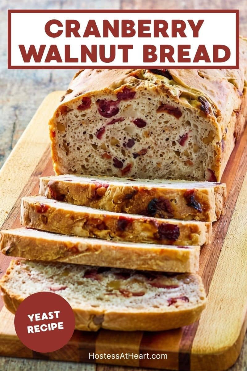 Front view of a sliced loaf of bread loaded with cranberries and walnuts sitting on a cutting board. Hostess At Heart