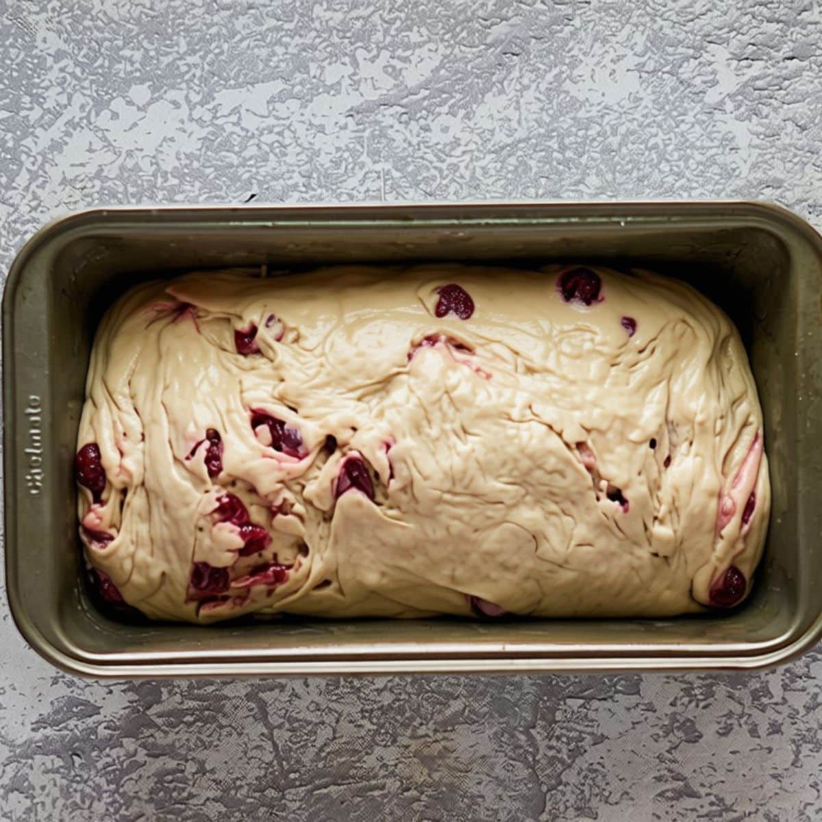 A shaped loaf of cranberry walnut dough in a bread loaf pan. Hostess At Heart