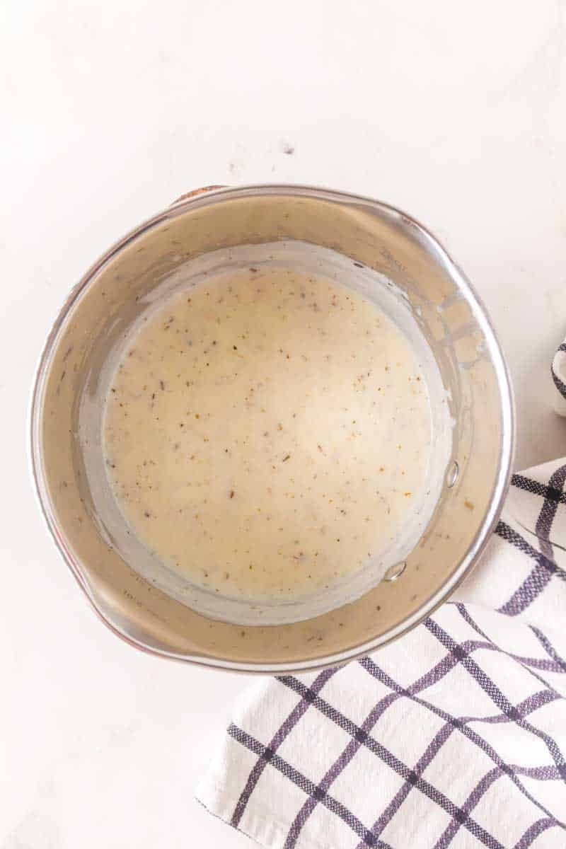 Milk being whisked into the butter and flour roux in a saucepan. Hostess At Heart