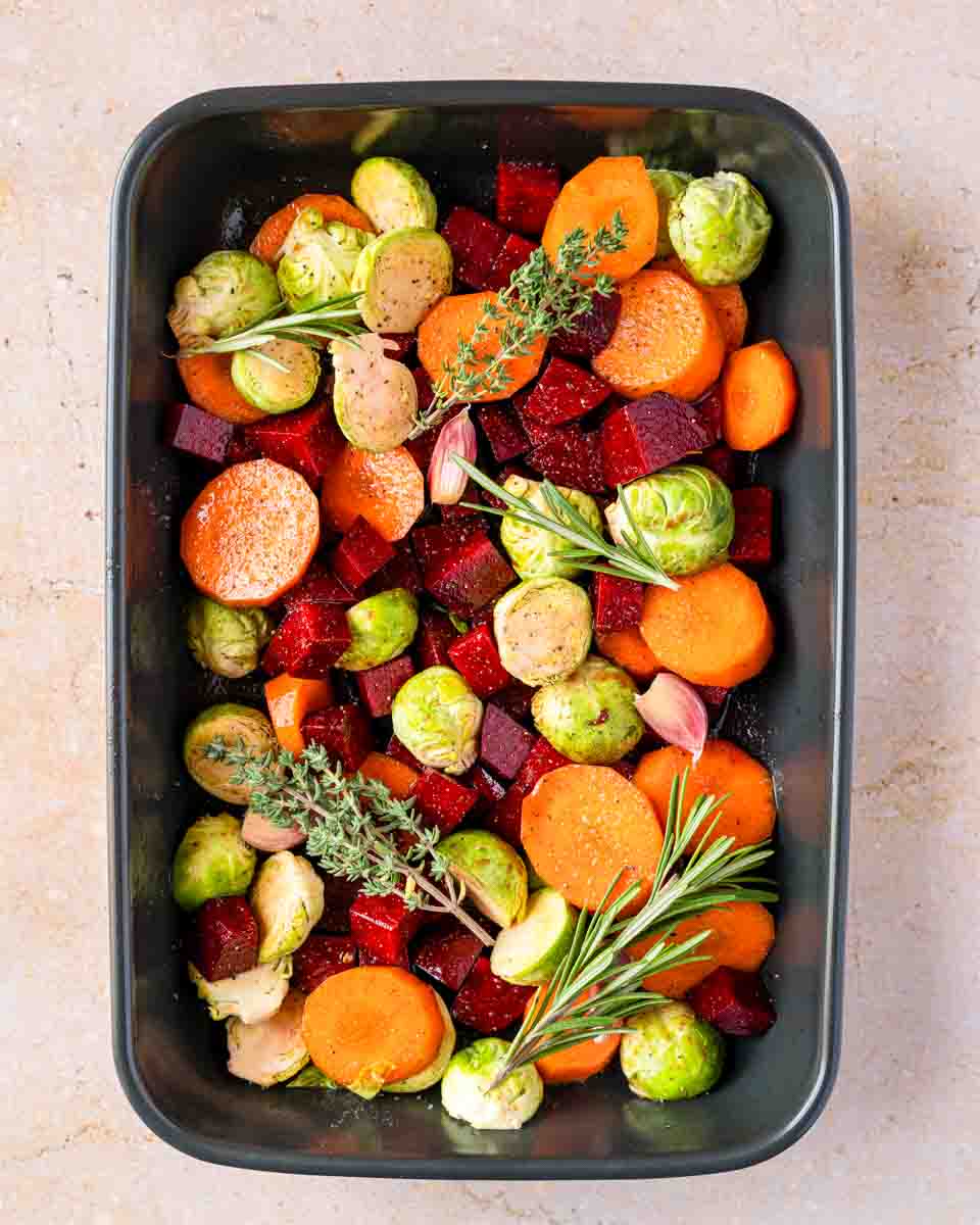 Halved Brussels sprouts added to the pan of partially roasted carrots and beets, topped with fresh herbs. Hostess At Heart