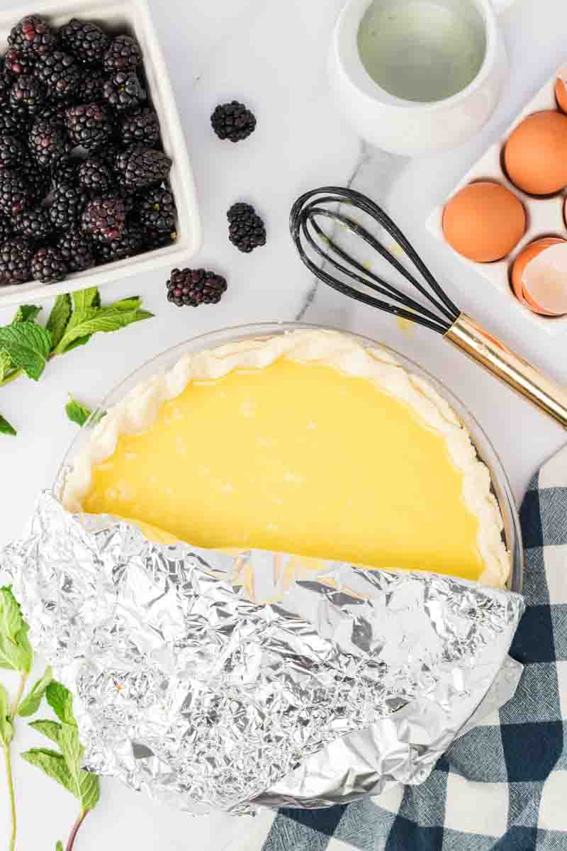 Buttermilk pie filled with creamy custard partially covered with foil before baking