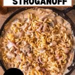 An image for Pinterest of a cast iron skillet filled with creamy leftover turkey stroganoff with mushrooms and egg noodles. Hostess At Heart