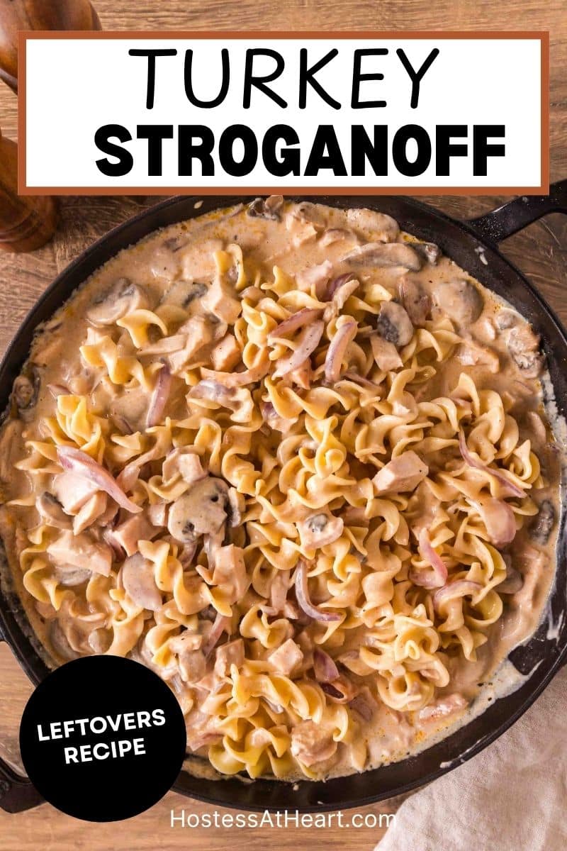 An image for Pinterest of a cast iron skillet filled with creamy leftover turkey stroganoff with mushrooms and egg noodles. Hostess At Heart