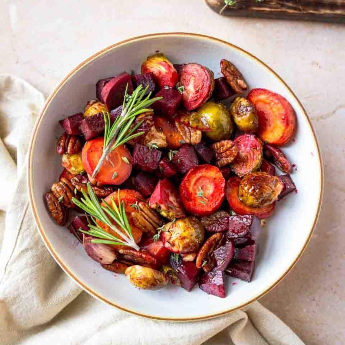 Roasted carrots, beets, and Brussels sprouts with pecans in a serving dish. Hostess At Heart