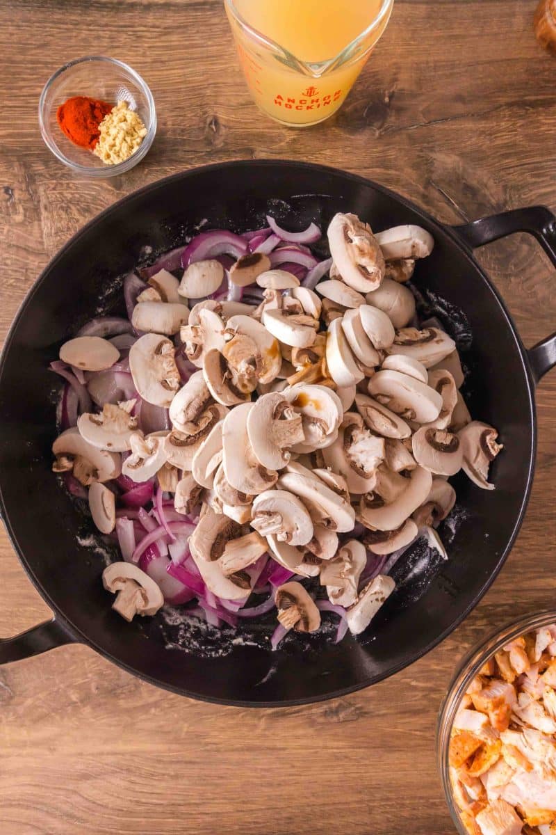 Sliced mushrooms added to a skillet filled with sauteed onions. Hostess At Heart