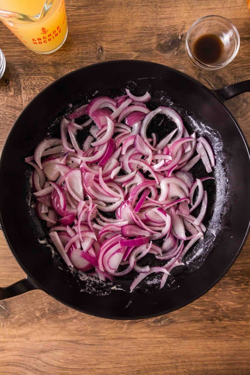 Sliced red onions cooking in butter in a large cast iron skillet. Hostess At Heart