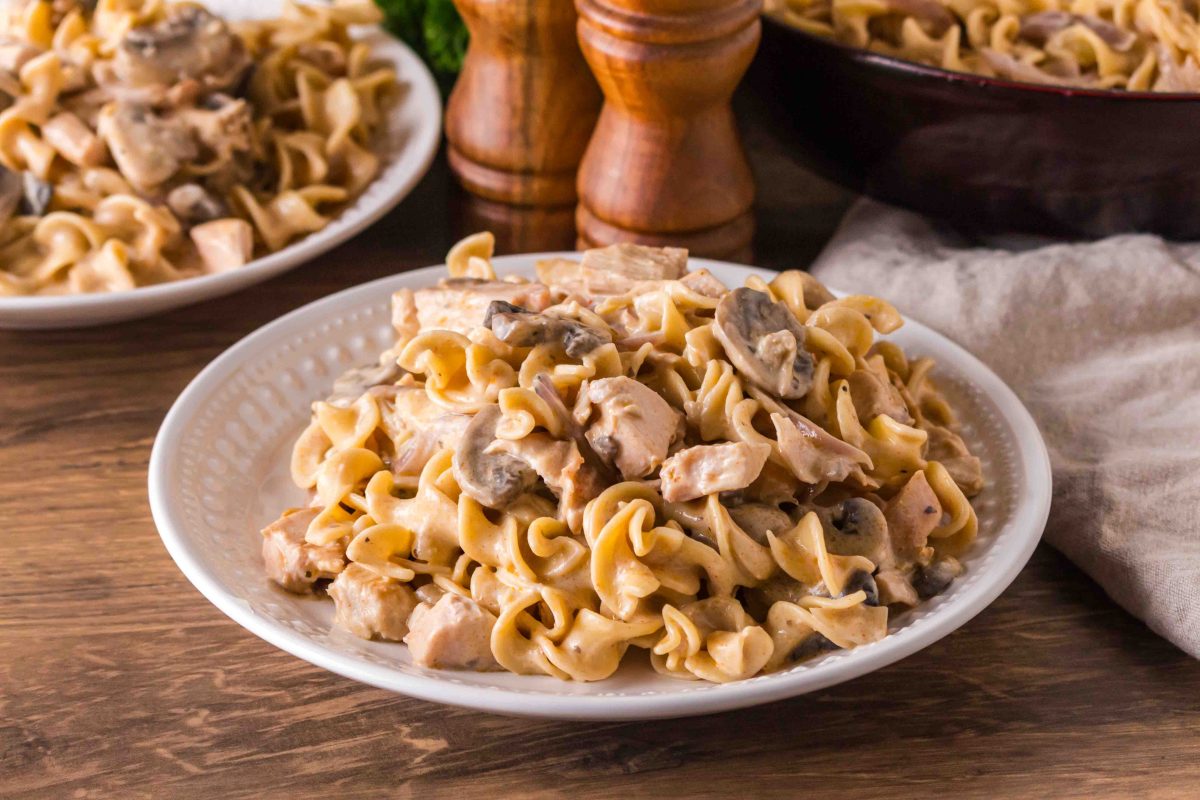 Cramy turkey stroganoff with mushrooms and egg noodles on a white plate. Hostess At Heart