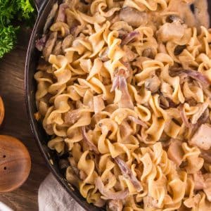 Top down view of a cast-iron skillet filled with creamy turkey stroganoff with mushrooms and egg noodles. Hostess At Heart