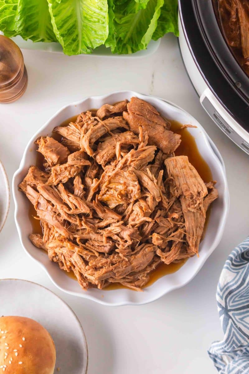 A serving dish filled with shredded pork tenderloin coated in BBQ sauce. Hostess At Heart